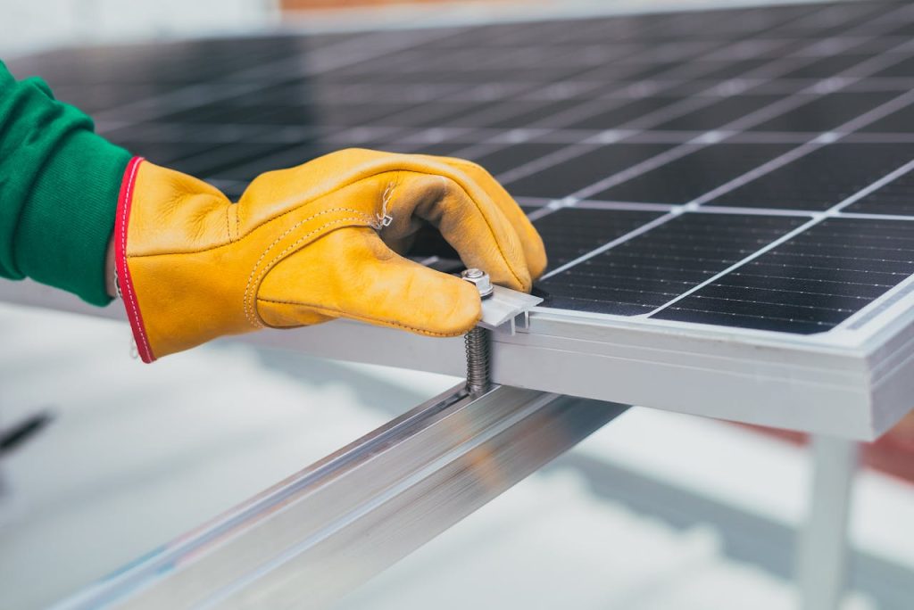 Close-up of a workers hand with protective gloves adjusting a bolt on a solar panel